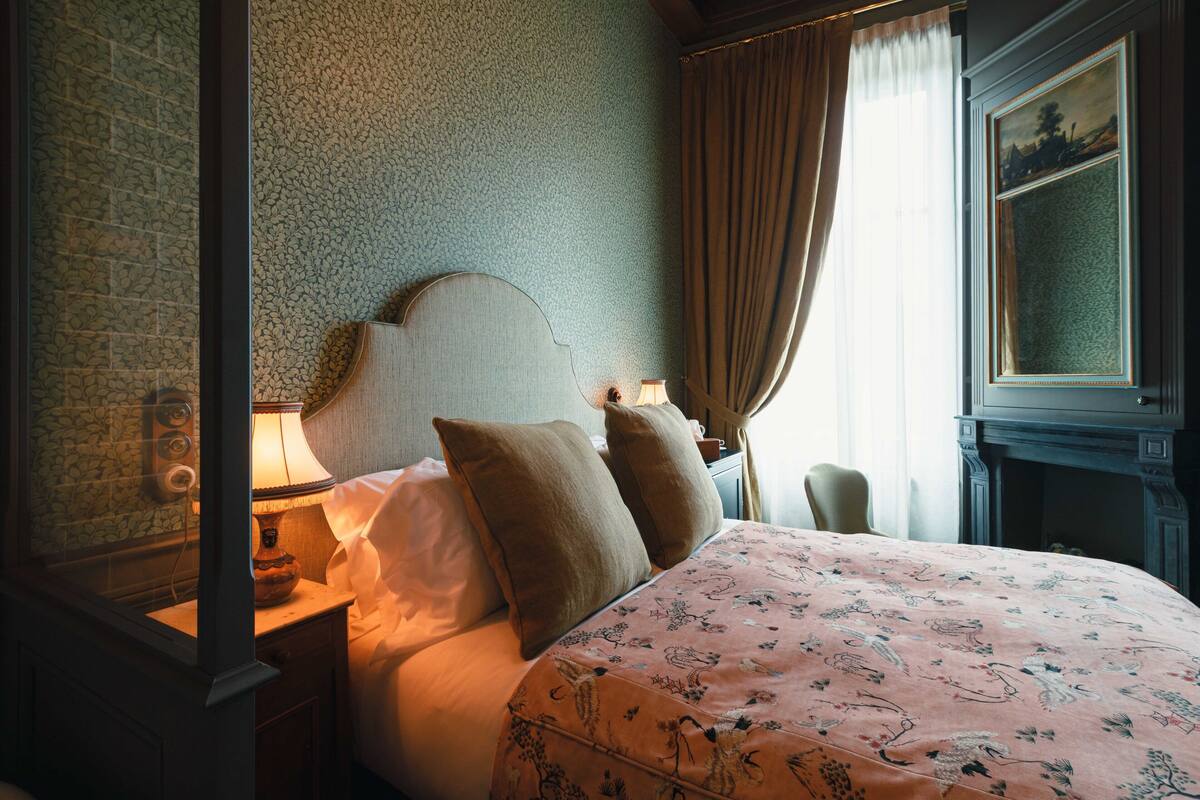 Une chambre à coucher avec un lit à baldaquin, une table de chevet avec une lampe, une chaise et un tableau au mur.