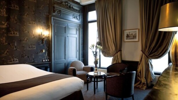 Une chambre d’hôtel avec un grand lit, une petite table ronde, deux chaises et un bureau.