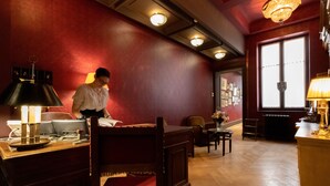 Un hall d’hôtel avec un mur rouge, des meubles en bois et des lustres.
