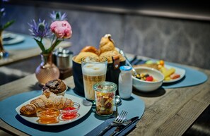 A table with a variety of food items including pastries, a glass of beer, and a fruit salad. - Hotel Westend (Nuremberg)