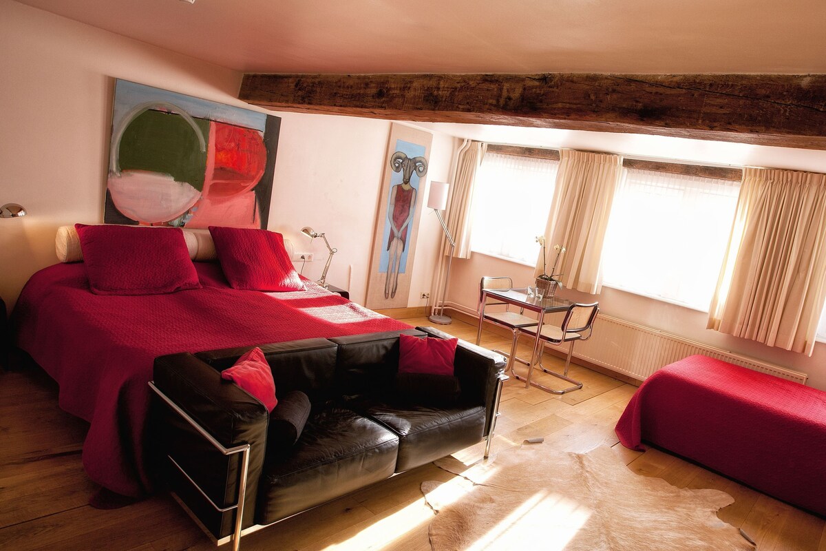 A room with a bed, a sofa, a small table, and a chair.