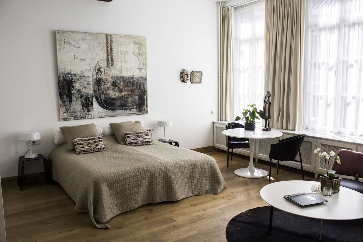A modern bedroom with a large bed, a round dining table, and a window with curtains.
