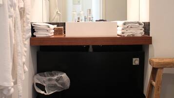 A bathroom with a sink, mirror, and a wooden stool.
