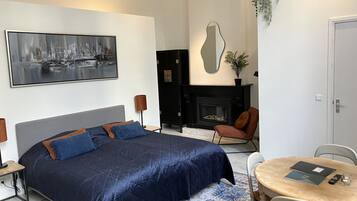 Une chambre moderne avec un grand lit, une cheminée, un coin repas et un grand miroir.