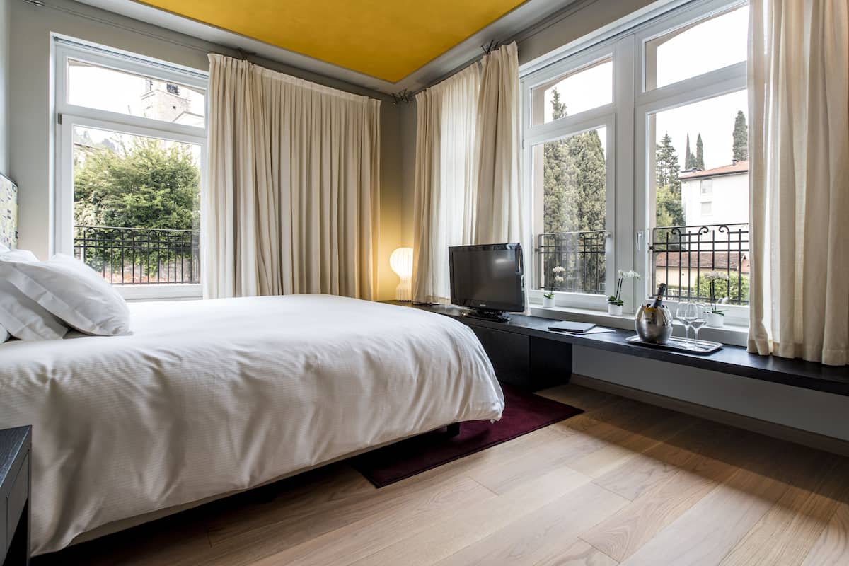 A bedroom with a bed, a TV, and a window with curtains.