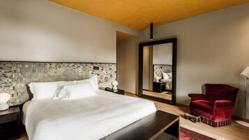 Ein modernes Hotelzimmer mit einem großen Bett, einem roten Sessel, einem Spiegel und einem Nachttisch aus Holz.