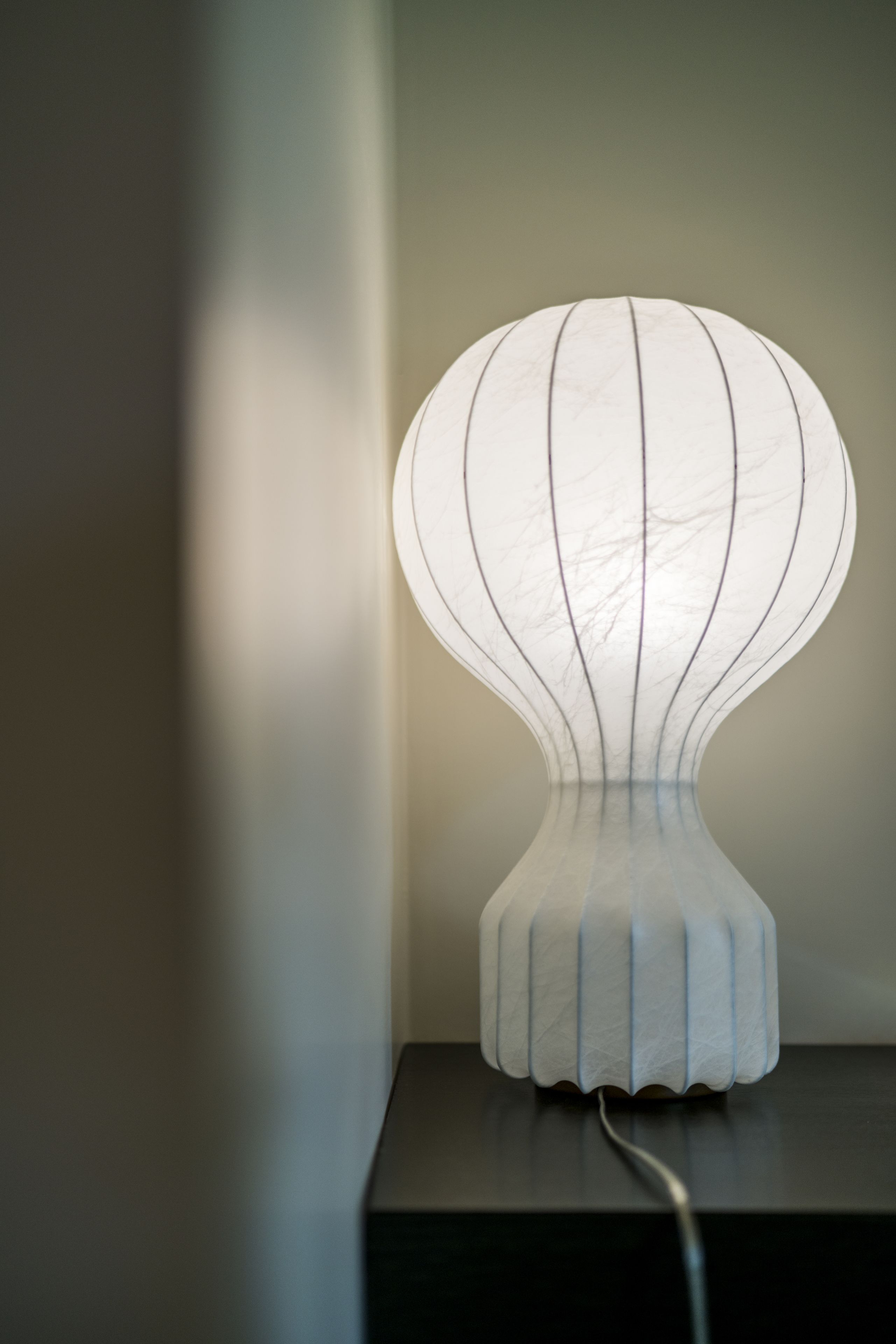 A modern, white, sculptural lamp on a black surface.