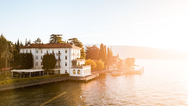 A large white building with multiple balconies and a waterfront view. - Hotel Bella Riva (Gardone Riviera)