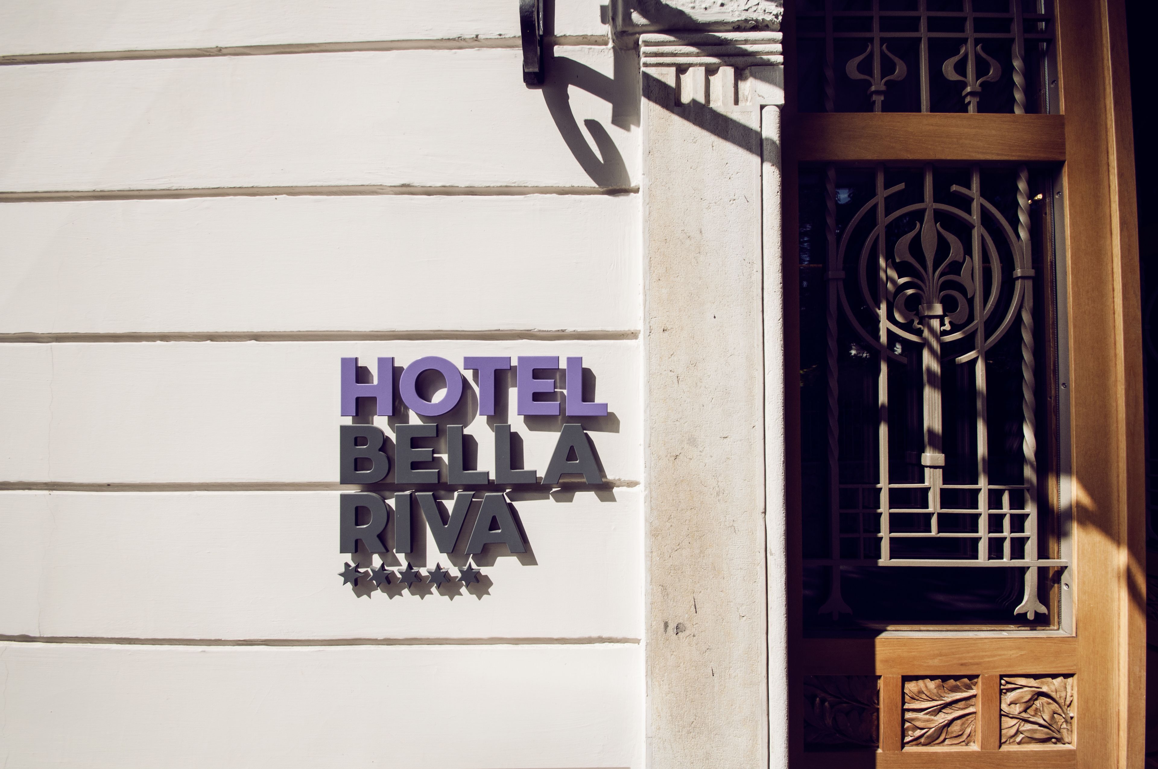 Een hotelschilt met de naam 'HOTEL BELLA RIVA' in grote, vetgedrukte letters.