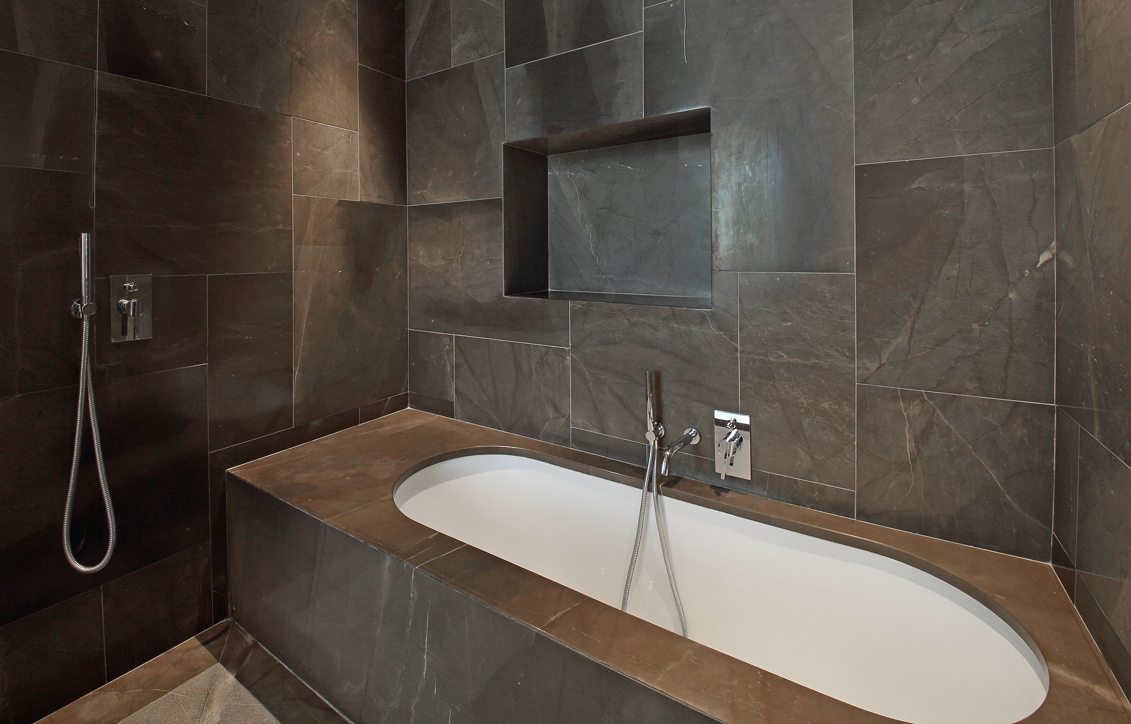 A modern bathroom with a freestanding bathtub, a showerhead, and a built-in shelf.