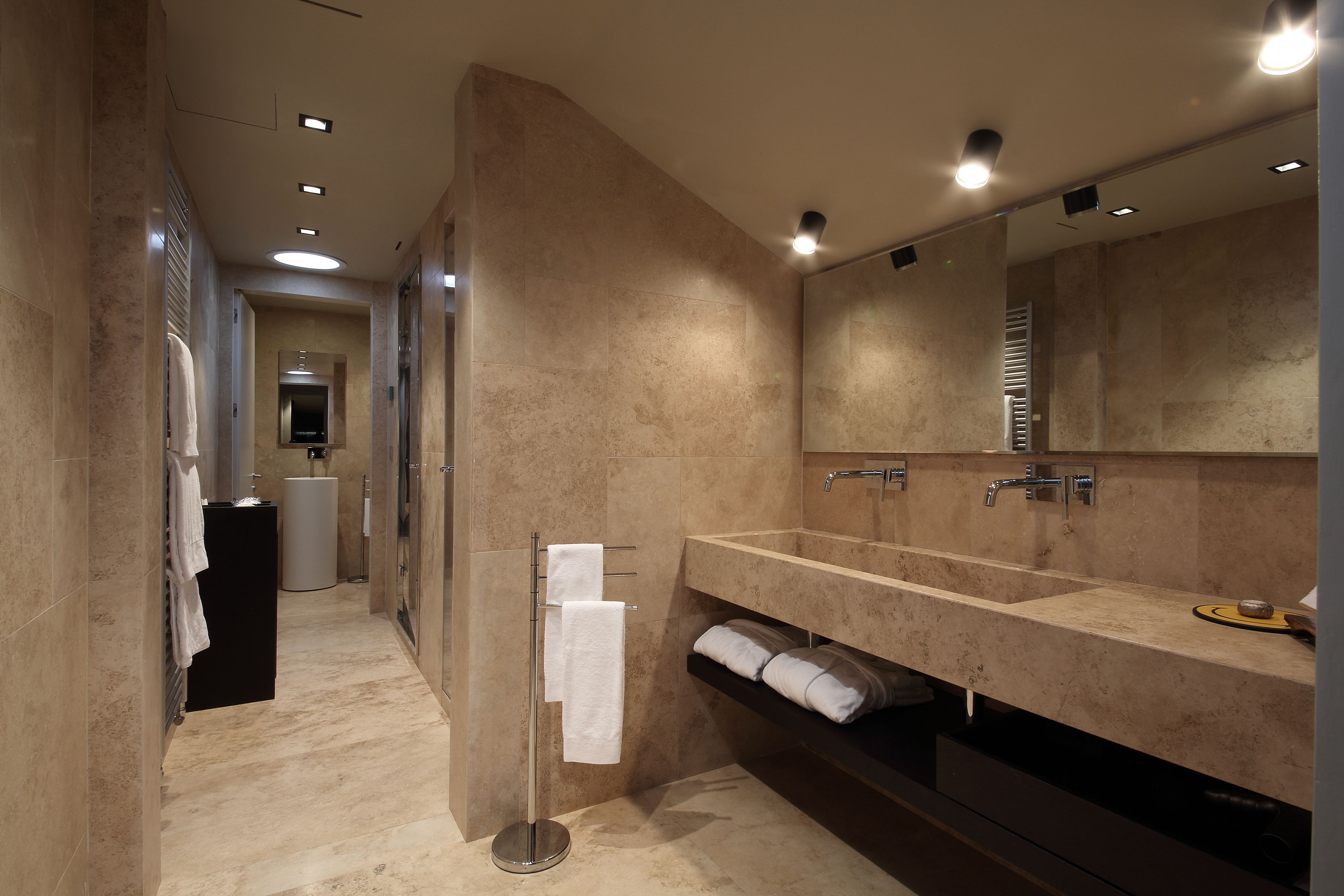 Une salle de bain moderne avec un grand miroir, deux lavabos et un porte-serviettes.