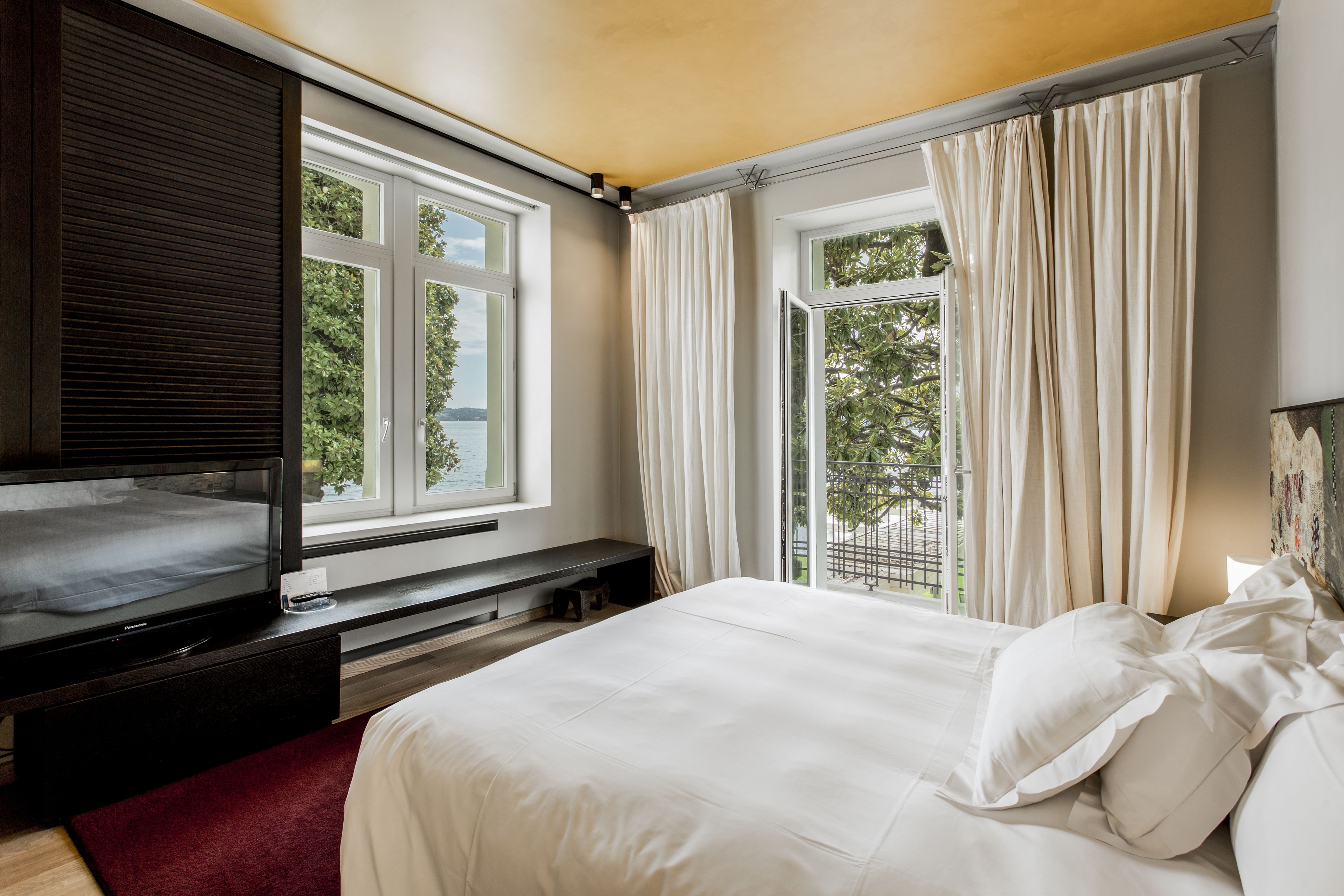 A bedroom with a bed, a TV, and a window with curtains.