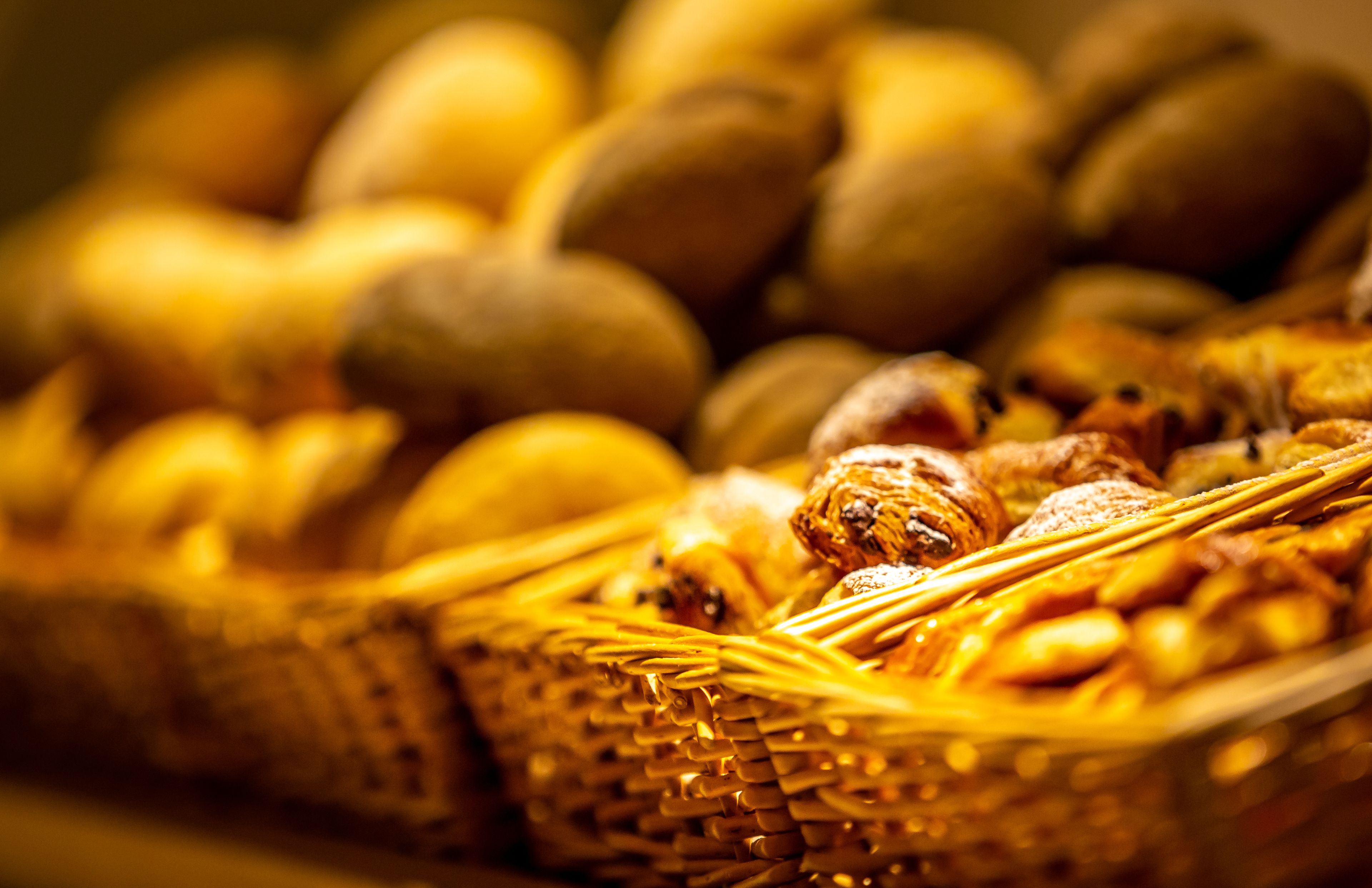 Un gros plan d’un panier en osier rempli de diverses pâtisseries, notamment des pains et des viennoiseries.