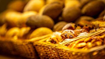 Un gros plan d’un panier en osier rempli de diverses pâtisseries, notamment des pains et des viennoiseries.