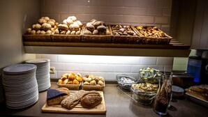 Monipuolinen buffetpöytä, jossa on tarjolla erilaisia leipiä, leivonnaisia ja juustolajitelmia.