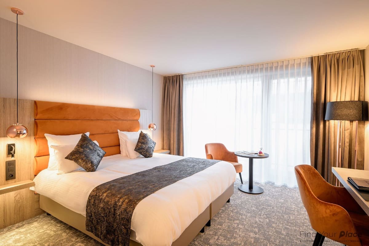 Una habitación de hotel con una cama grande, un escritorio, una silla y una mesita.