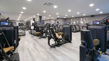 A modern gym with various exercise machines, treadmills, and weight stations.