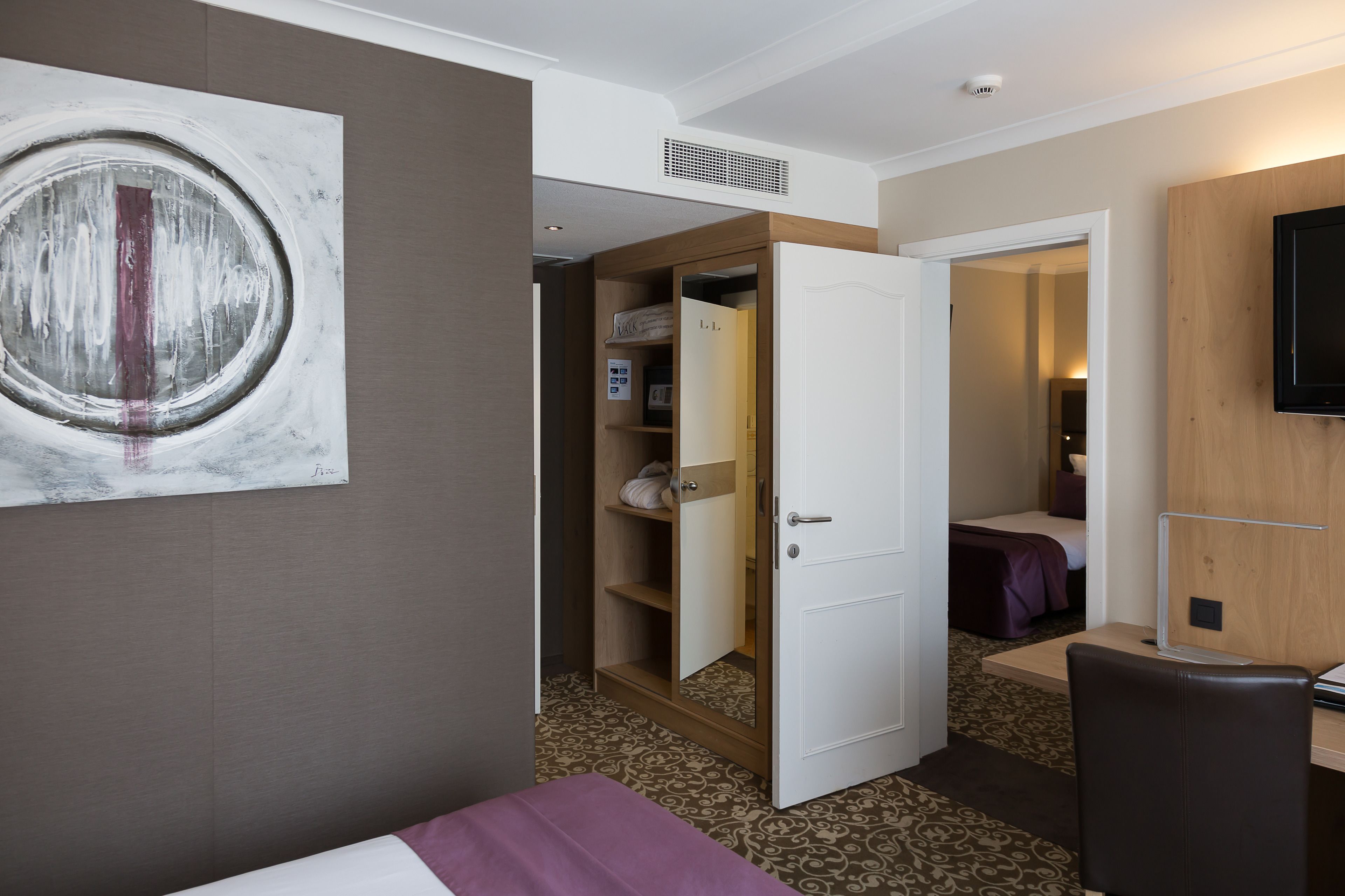 Une chambre d’hôtel équipée d’un lit, d’un bureau, d’une chaise, d’une armoire et d’un téléviseur.