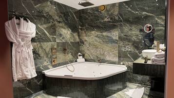 Un baño moderno con una bañera independiente, paredes de mármol y un tocador con espejo.