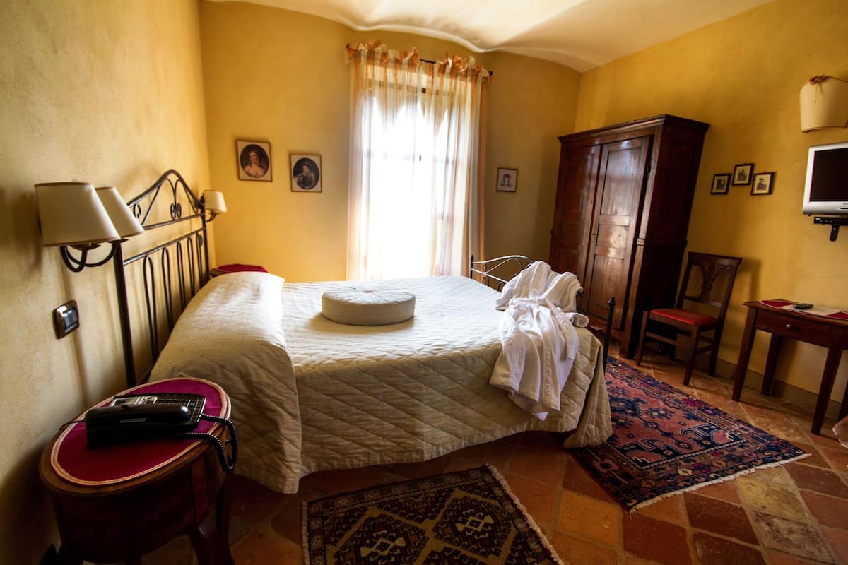 A hotel room with a bed, a chair, a desk, a television, and a bathroom.