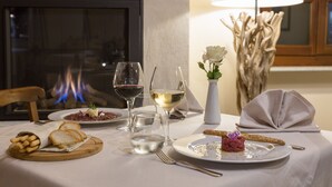 A dining table set with plates of food, glasses of wine, and a candle holder. - Castello di Razzano, The Originals Relais (Relais du Silence) (Alfiano Natta)
