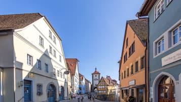 Eine Kopfsteinpflasterstraße gesäumt von historischen Gebäuden, darunter ein Uhrturm und verschiedene Geschäfte.