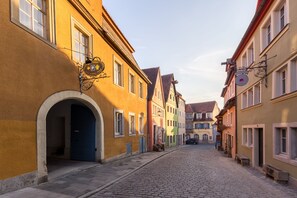 A cobblestone street lined with colorful buildings, each with distinct architectural features and signage. - Hotel Goldener Hirsch (Rothenburg ob der Tauber)