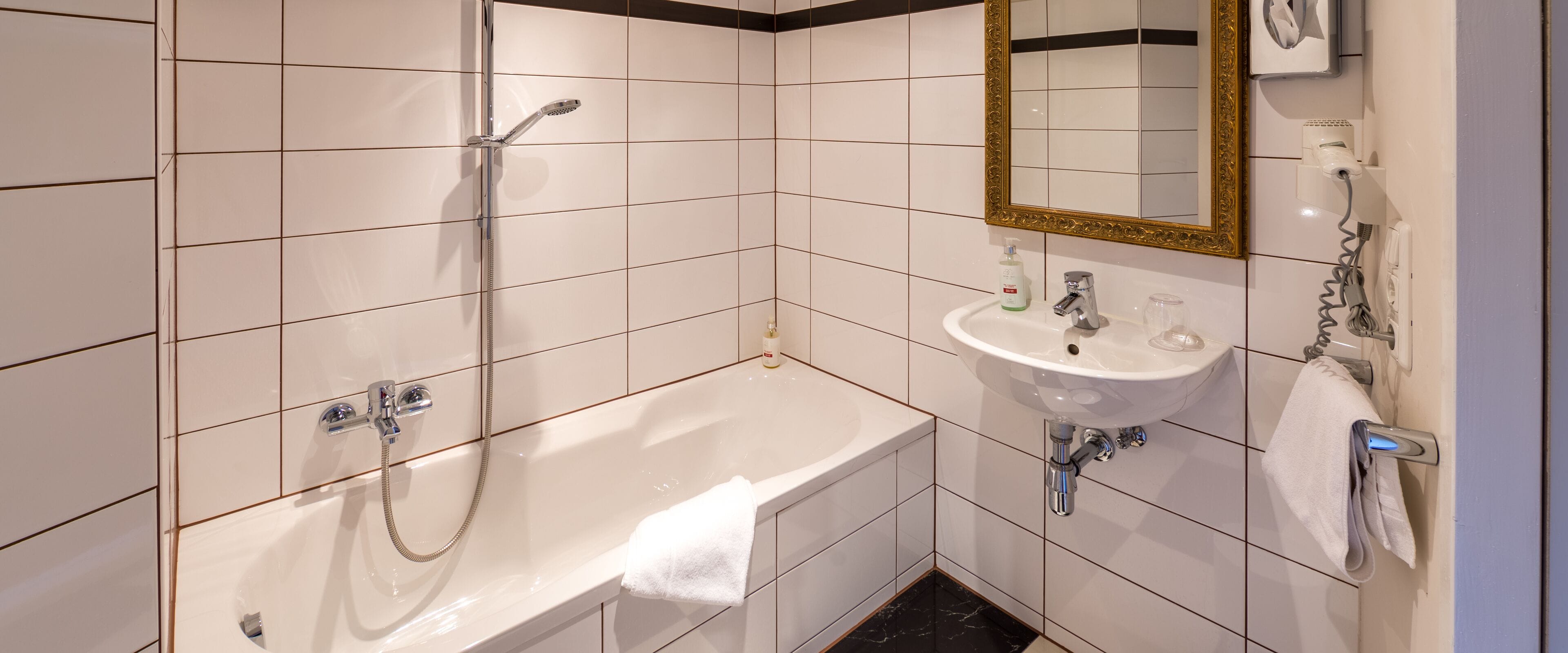 Un baño con bañera, lavamanos, espejo y ducha.