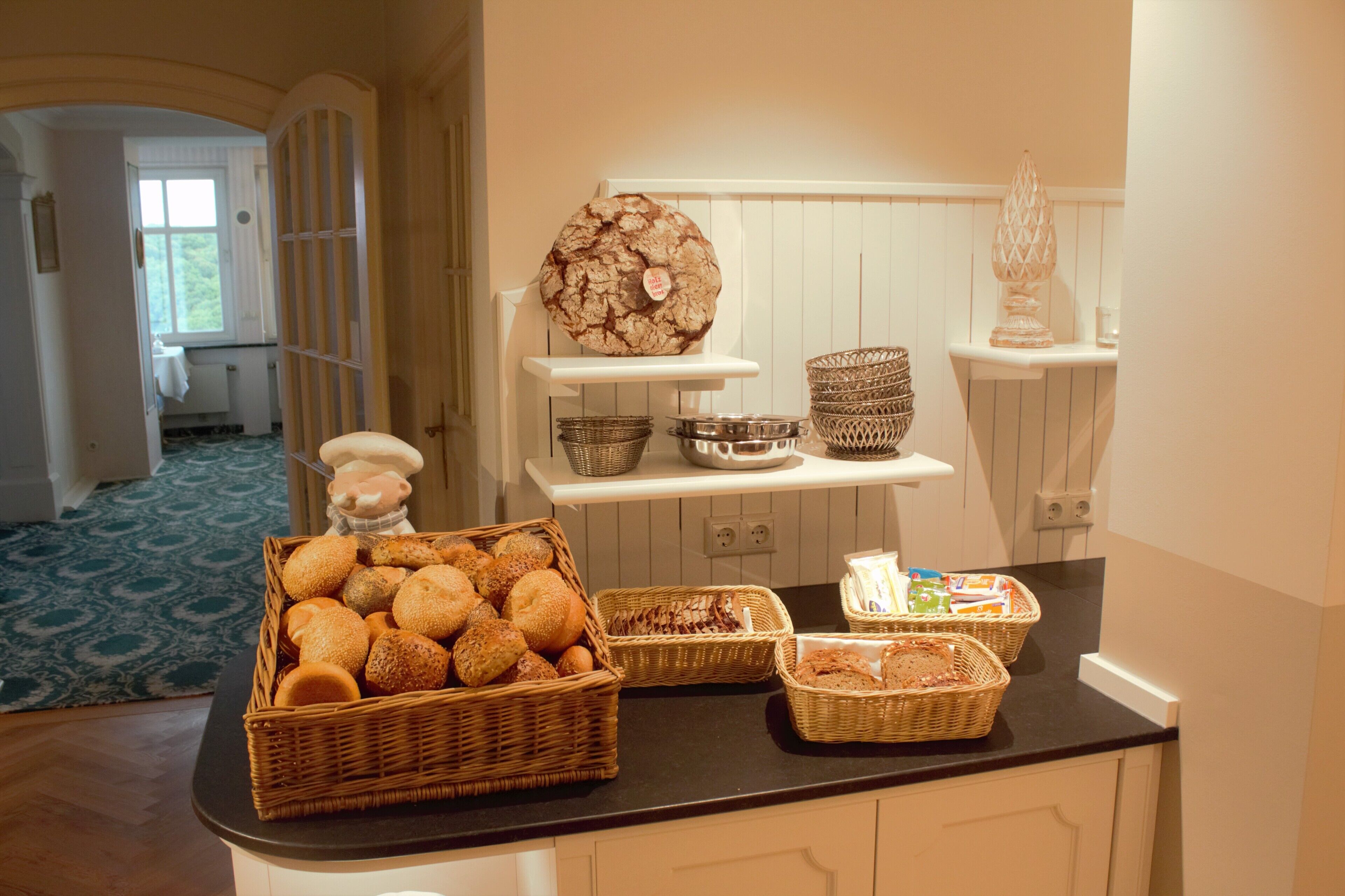 A kitchen counter with various baskets of bread and pastries.