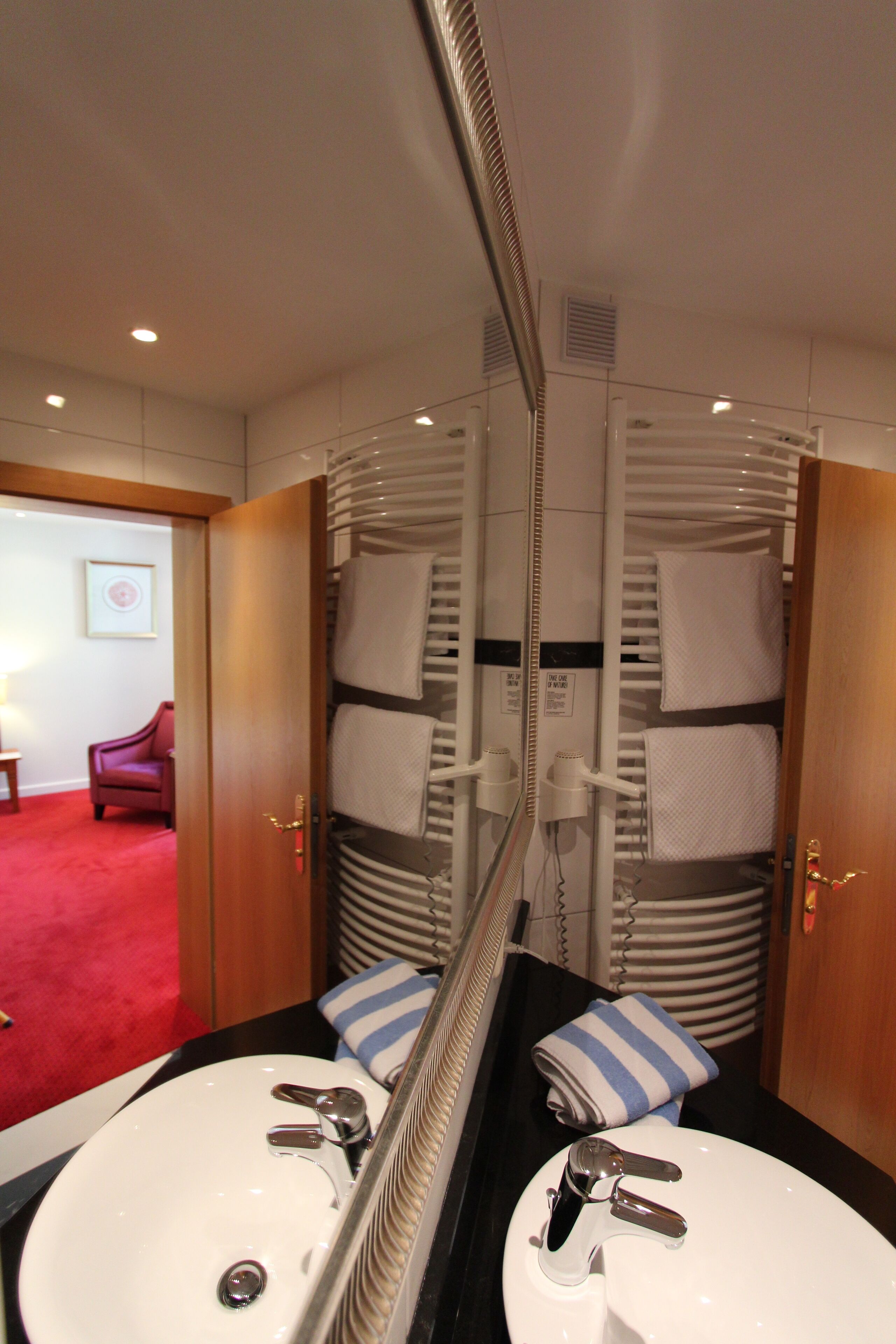 A bathroom with two sinks, a mirror, and a towel rack.