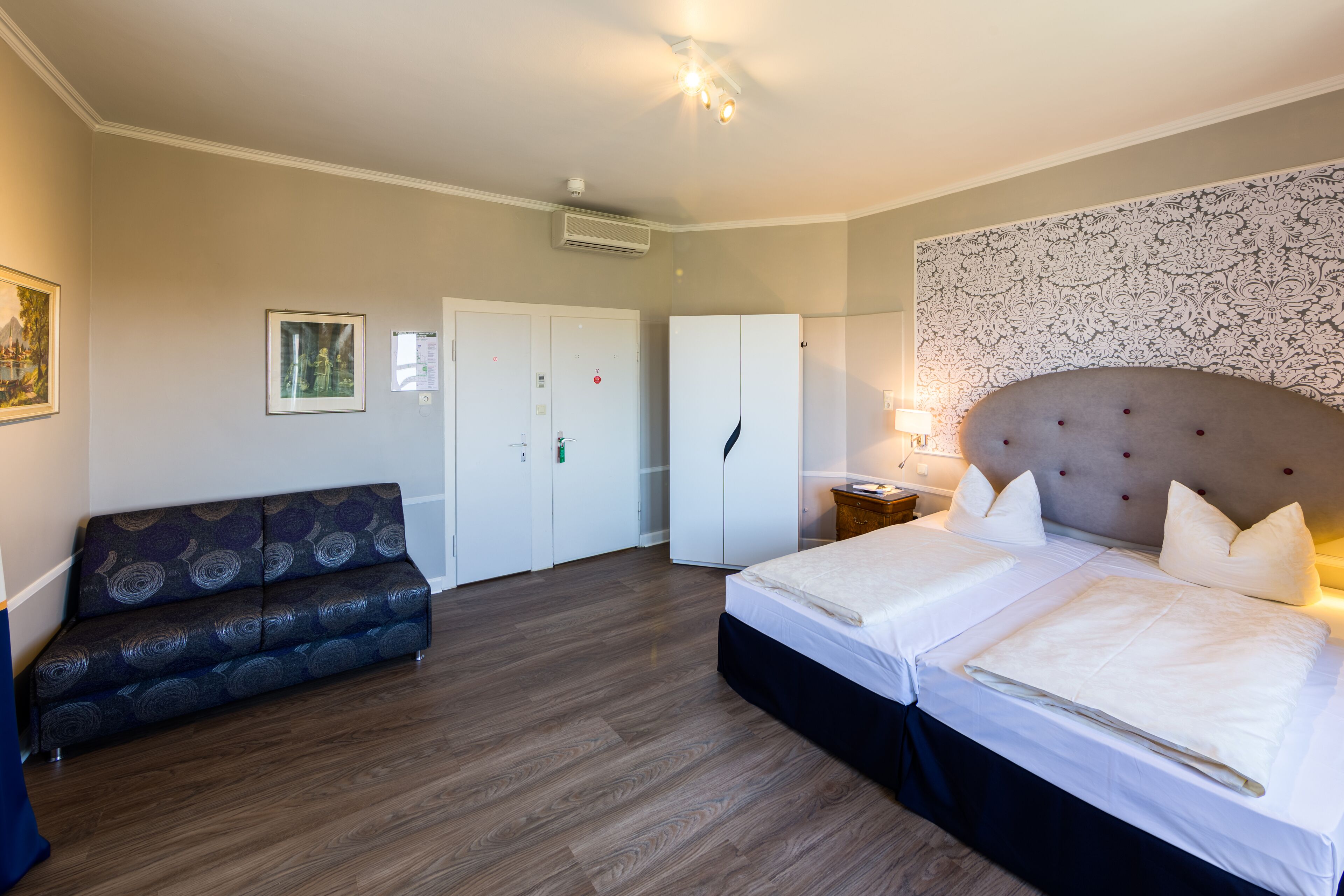 Un dormitorio con cama, sofá, armario y una pared con diseño decorativo.