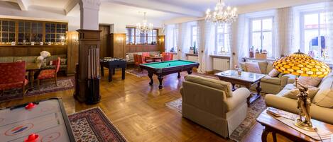 Un salón amplio con mesa de billar, asientos cómodos y una zona de bar.