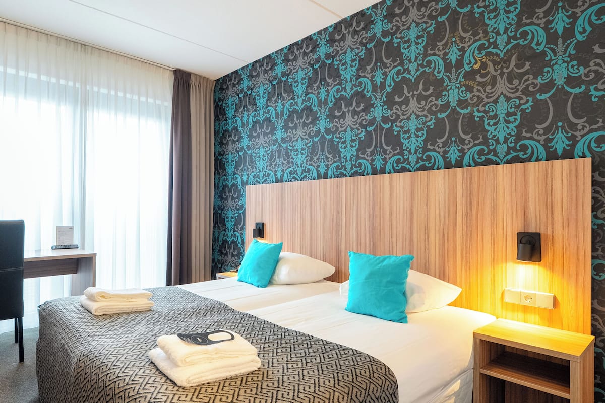 A hotel room with two beds, a desk, and a chair.