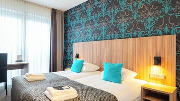 A hotel room with two beds, a desk, and a chair.