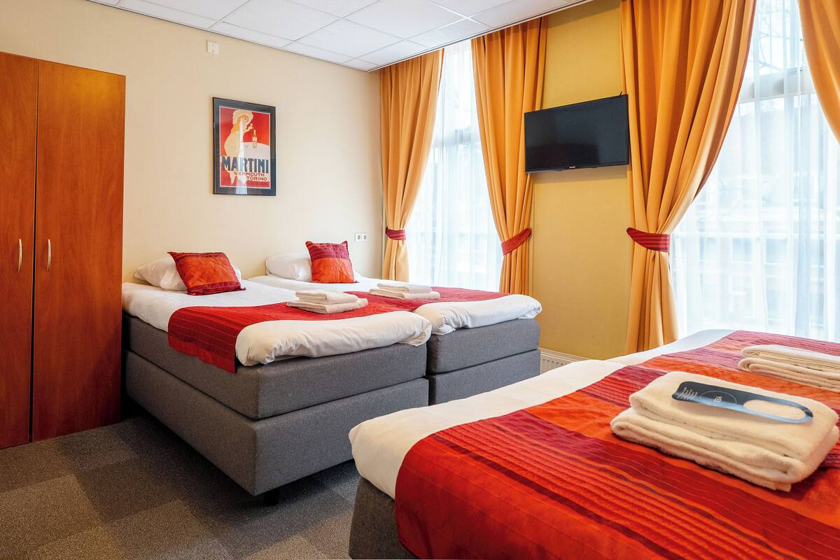 A hotel room with two beds, a TV, and a poster on the wall.