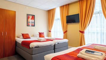 Una habitación de hotel con dos camas, un televisor y un cartel en la pared.