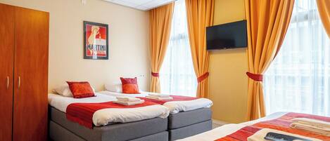 Una habitación de hotel con dos camas, un televisor y un cartel en la pared.