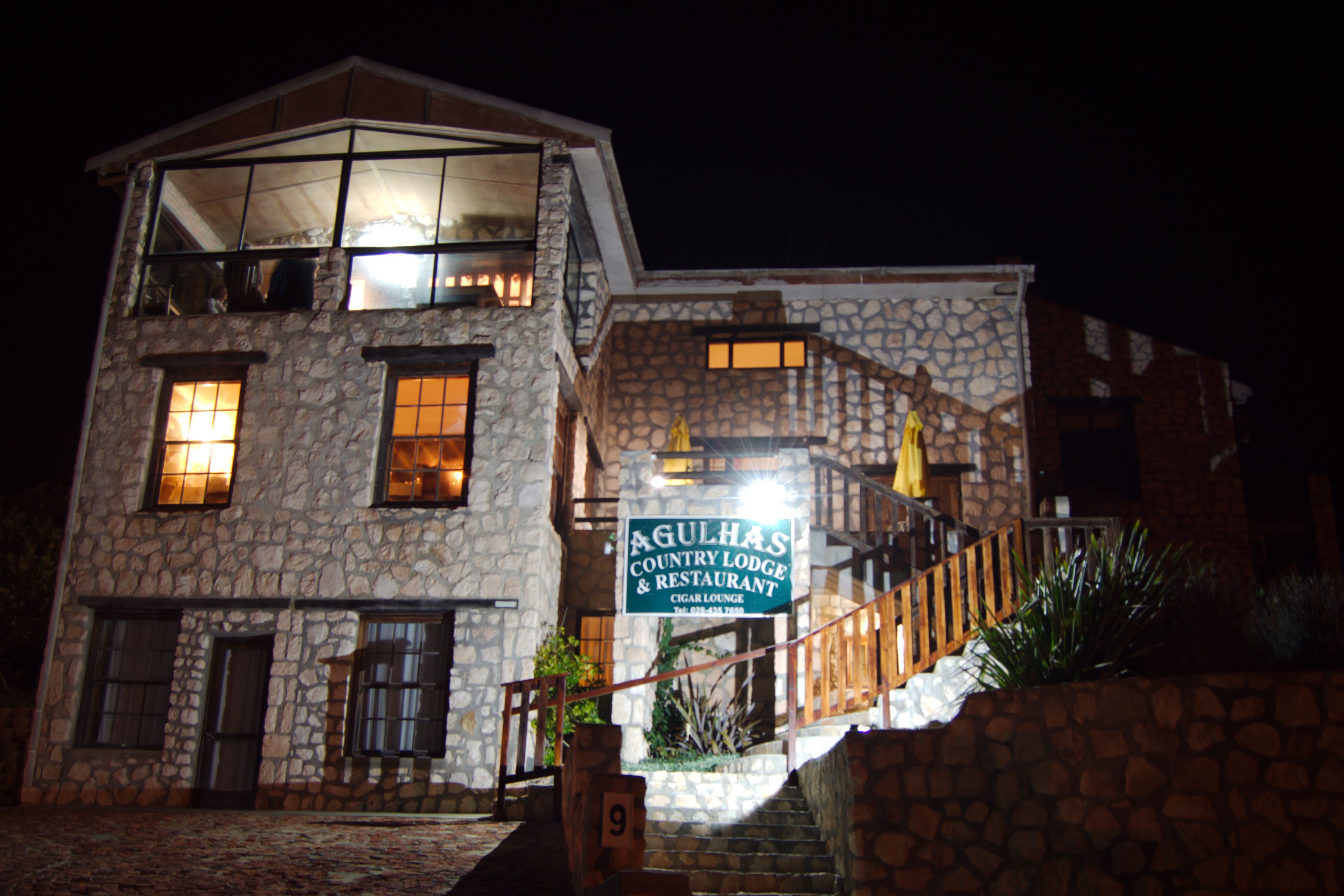 A stone building with a sign for 'Agulhas Country Lodge & Restaurant'.