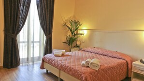 A neatly made bed with a pink quilt, two rolled towels, and a bedside table with a lamp. - Il Monte (Monte San Savino)