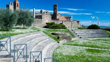 Un edificio de piedra histórico con una torre, rodeado de un muro de piedra y escalones que conducen a él.