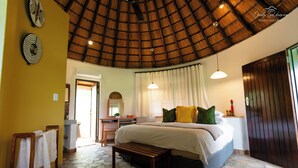 A bedroom with a large bed, a wooden bench, a desk, and a wardrobe. - Mohlabetsi Safari Lodge (Hoedspruit)
