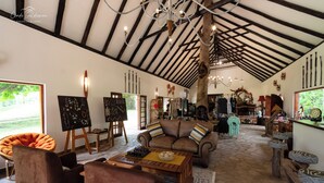 A spacious room with a high ceiling, a large wooden table, a comfortable sofa, and a chessboard. - Mohlabetsi Safari Lodge (Hoedspruit)