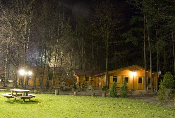 A wooden cabin with a porch, surrounded by trees.