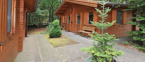 A wooden cabin with a porch, a bench, and a potted plant.
