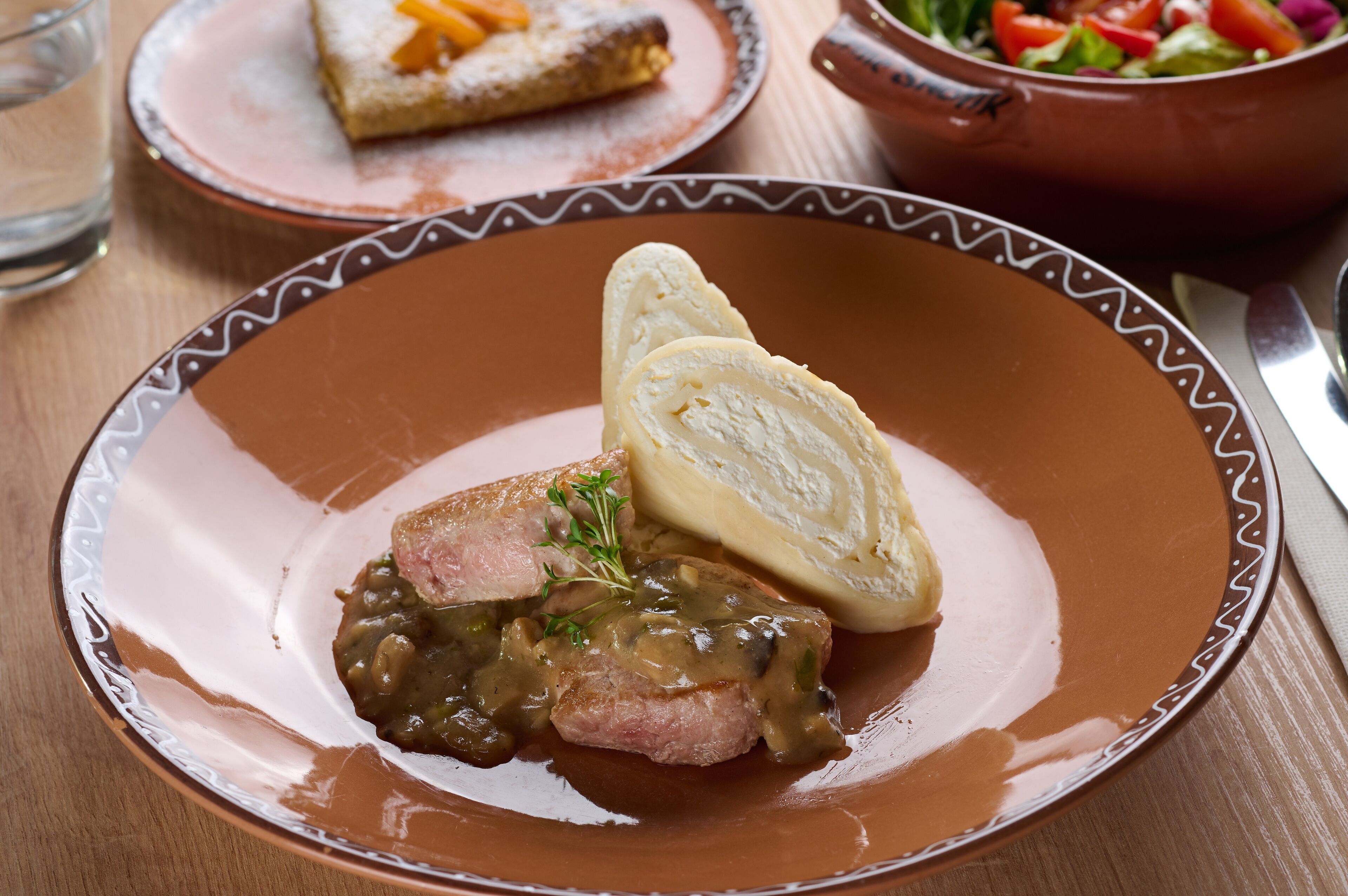 Un plato con un trozo de carne, puré de papas y salsa verde.