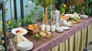 Un bufé de desayuno con diversos alimentos, como frutas, pasteles y sándwiches, dispuesto sobre una mesa con mantel morado.