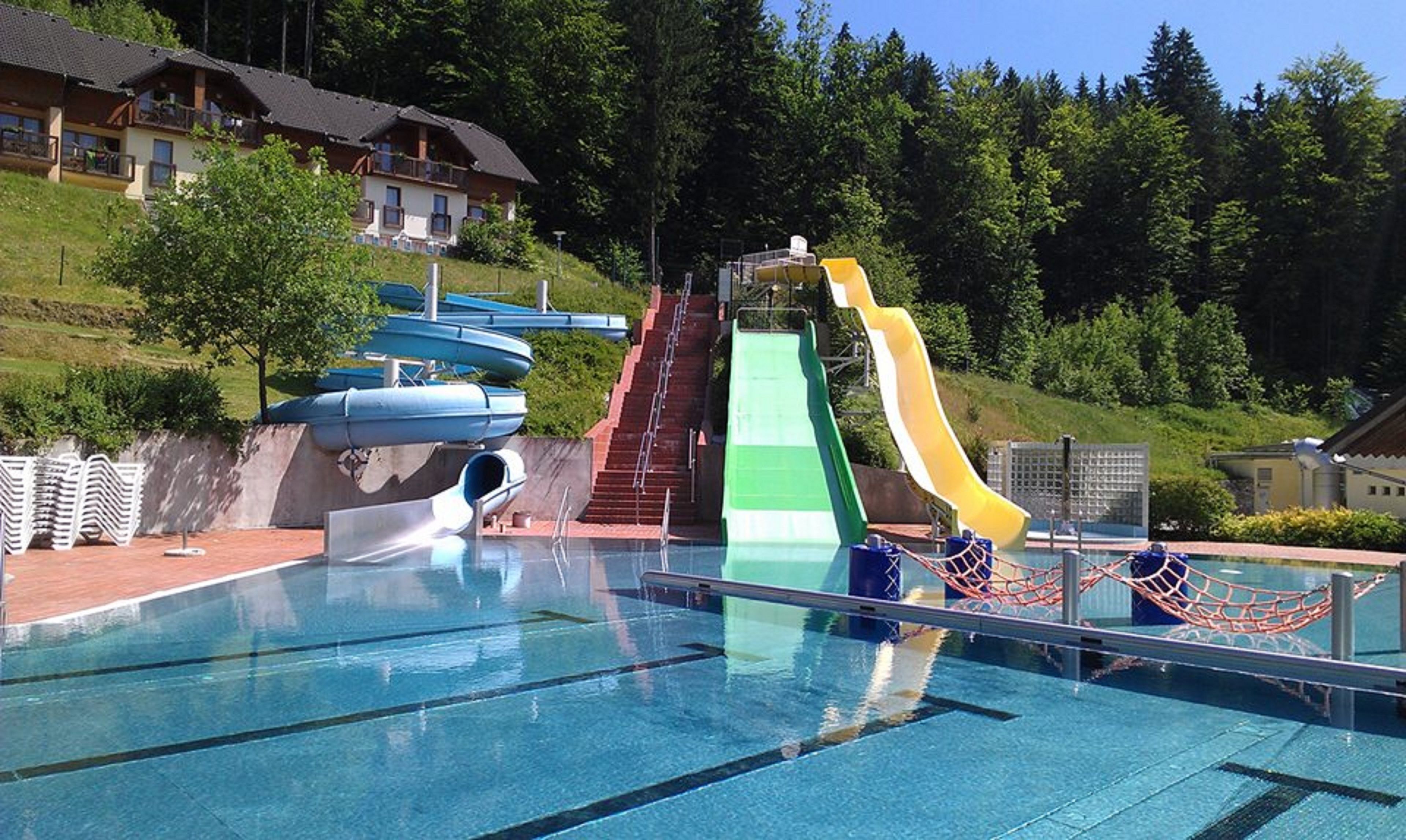 A swimming pool with multiple slides and a netted area.