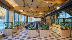 Una sala de conferencias con suelo de patrón hexagonal, vigas de madera en el techo y filas de sillas.