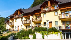 Una hilera de edificios de varios pisos con balcones, barandillas de madera y fachada de piedra.