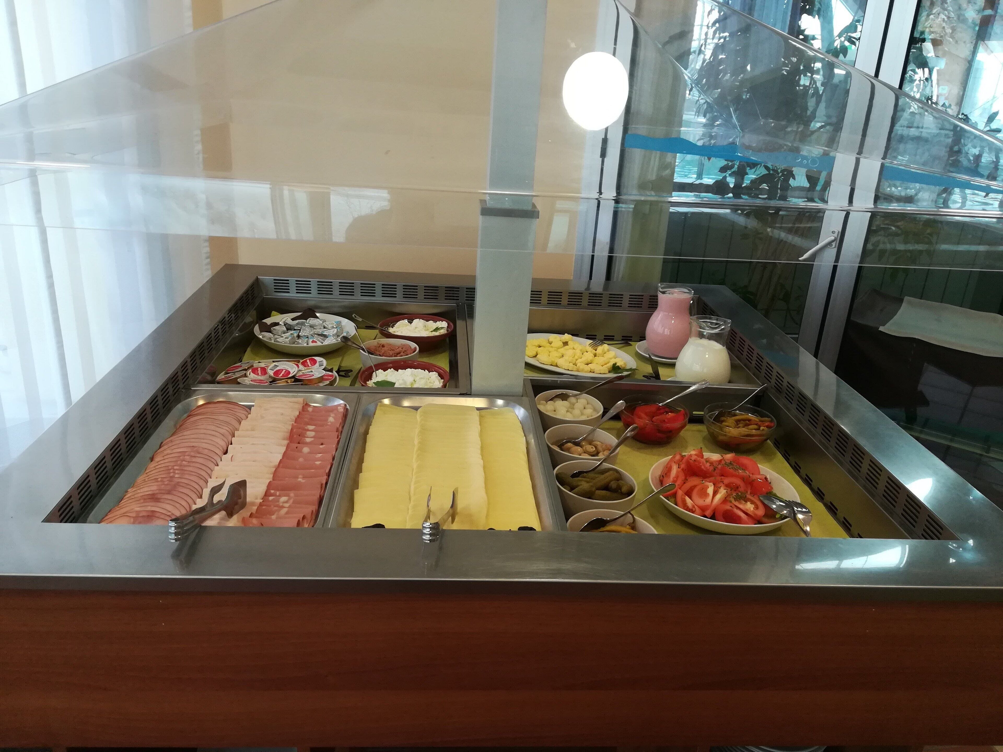 Buffet com diversos alimentos, incluindo carnes, queijos e legumes.